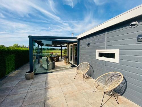 a patio with two chairs and a building at LuxChalet Ferienhaus ELLA mit Aussicht auf die Ijssel im Ferienpark mit Pool und Strand Holland Niederlande in Lathum