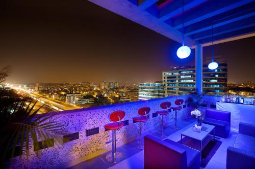 a rooftop bar with red chairs and a view of a city at ibis Bengaluru Hosur Road - An Accor Brand in Bengaluru