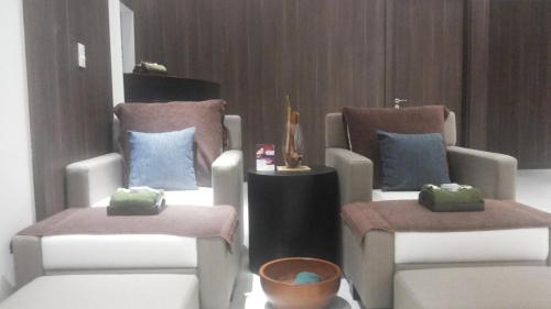 two chairs with pillows and a table in a room at Mercure Karawang in Karawang