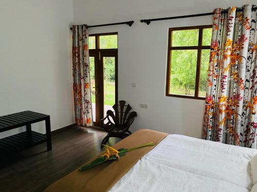 a bedroom with a bed and two windows with curtains at Villa Sukka in Tangalle