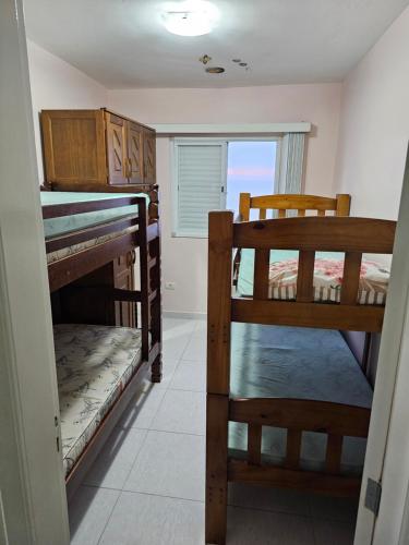 two bunk beds in a room with a window at Apartamento frente mar pé na areia in Praia Grande