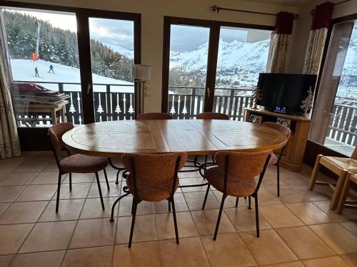 - une table et des chaises dans une pièce avec une piste de ski dans l'établissement Appartement Cosy EDEN des CîMES 6 à 8 couchages, à Saint-Étienne-en-Dévoluy