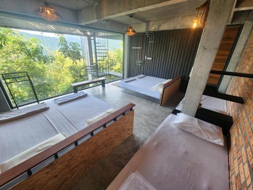 a room with two beds and a large window at The Wildwood Retreat KKB in Kuala Kubu Baharu