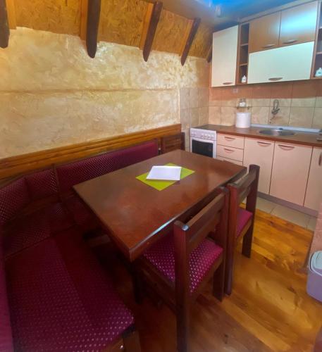 a kitchen with a wooden table and red chairs at Apartman Zlatarske Čari in Nova Varoš