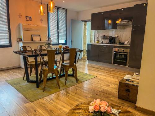 une cuisine et une salle à manger avec une table et des chaises dans l'établissement La Suite du Triomphe - Bain Balnéothérapie,Netflix, à Montpellier