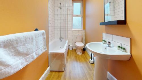 Un baño con dos lavabos, una bañera y un inodoro. en Unique 3Bed Home Free Parking Near Meadowhall, en Brightside