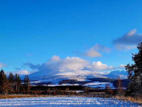 a snow covered mountain in the middle of a field at Bespoke Luxury Self Catering Dog Friendly Accommodation in Archiestown