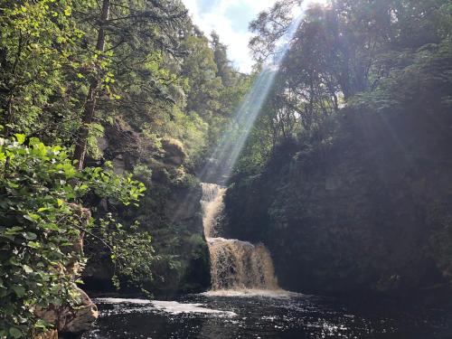 a waterfall in the middle of a river in a forest at Bespoke Luxury Self Catering Dog Friendly Accommodation in Archiestown