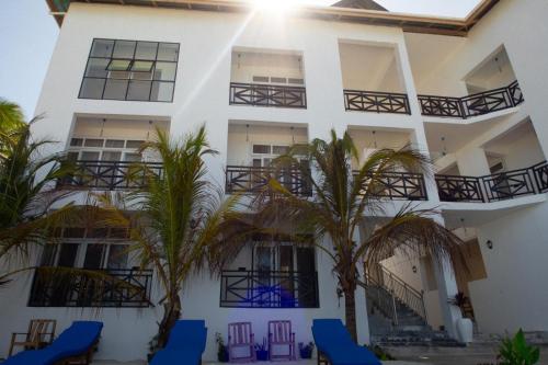 a white building with palm trees and blue chairs at Mia Boutique Hotel in Michamvi