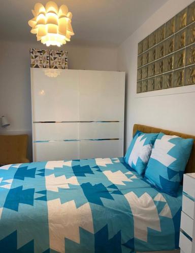 - une chambre avec un lit bleu et blanc et un lustre dans l'établissement Appartement cosy proximité gare de Saint Cloud, à Saint-Cloud