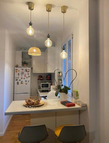 une cuisine avec un comptoir avec deux chaises et des lumières dans l'établissement Appartement cosy proximité gare de Saint Cloud, à Saint-Cloud