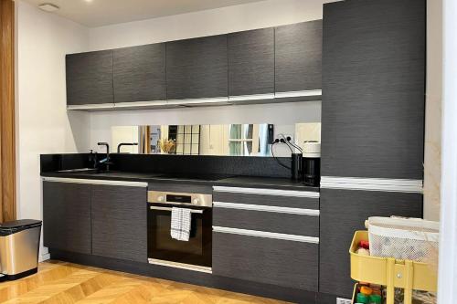 - une cuisine avec des placards noirs et un évier dans l'établissement Cozy T3 with Wifi in the heart of Vauban, à Marseille