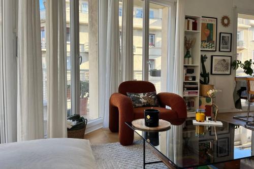 - un salon avec une chaise et de grandes fenêtres dans l'établissement Cozy T3 with Wifi in the heart of Vauban, à Marseille