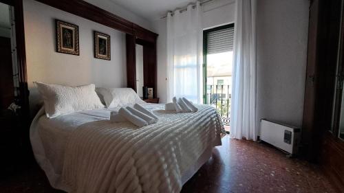 a bedroom with a bed with white sheets and a window at LaCasa DeLola in Almodóvar del Río