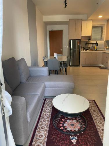 a living room with a couch and a table and a kitchen at RaaNest, Sunsuria Forum in Shah Alam