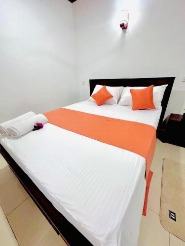 a bedroom with two beds with orange and white pillows at Angel Villa Unakuruwa Tangalle in Tangalle