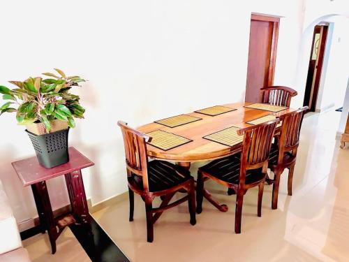 a dining room table with four chairs and a potted plant at Angel Villa Unakuruwa Tangalle in Tangalle