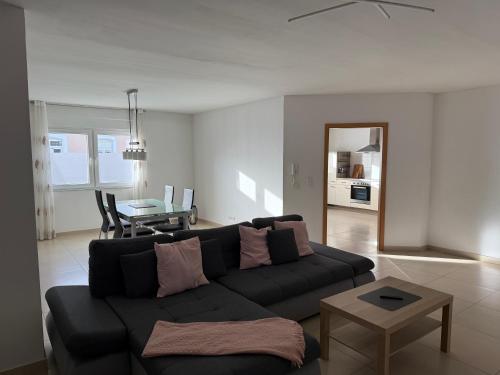 Una sala de estar con un sofá negro y una mesa. en Ferienwohnung Benjamin, en Clausen