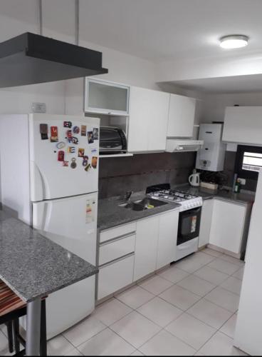 eine Küche mit weißen Schränken und einem weißen Kühlschrank in der Unterkunft Dos Nogales 26 in Villa Carlos Paz