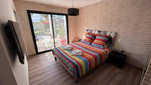 - une chambre avec un lit et une couverture colorée dans l'établissement Maison de 102m² sur terrain clos terrasse Jacuzzi, à Le Tour-du-Parc