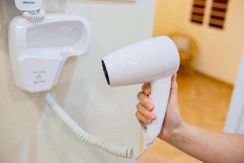 a hand holding a blow dryer next to a phone at Skudai Tun Aminah Cozy Home - Sutera Mall 6 mins in Skudai