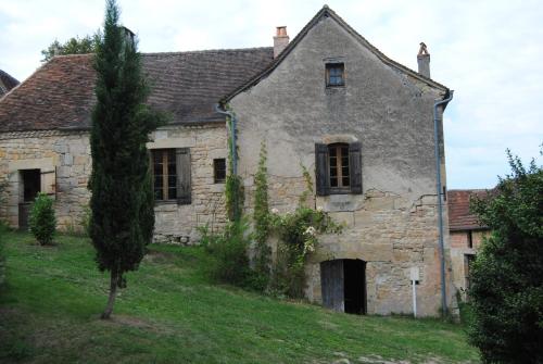 an old stone house with a tree in the yard at Gîte de charme 4 étoiles avec piscine privée in Cherveix-Cubas
