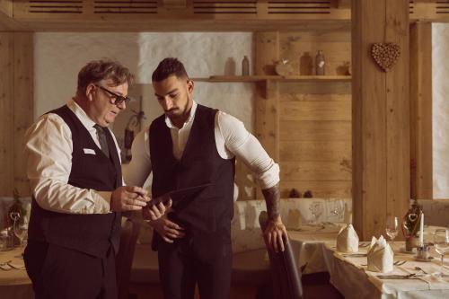 two men standing in a kitchen looking at a table at Hotel Sonnalp in Kirchberg in Tirol