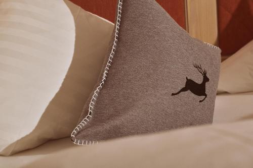 a pillow with a deer on it on a bed at Hotel Sonnalp in Kirchberg in Tirol