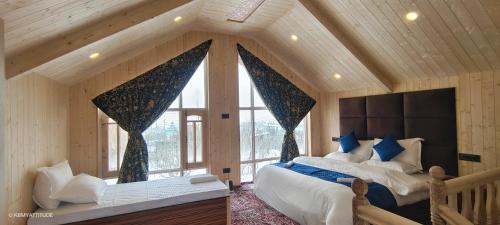 a bedroom with two beds and a large window at Countryside Cottage Gulmarg in Tangmarg
