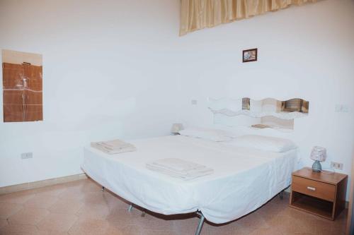 a white bed in a room with a white wall at Appartamento con vista mare in Palmi