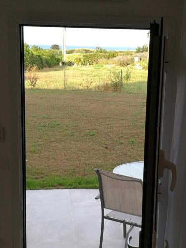 a door open to a patio with a table and a field at Chambres 2-3 pers à 600m de la plage de Kerhillio - Erdeven plage in Erdeven