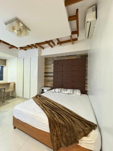 een slaapkamer met een groot bed met een houten hoofdeinde bij Modern Cozy with Netflix Condo Unit in Calyx Cebu Ayala in Cebu City