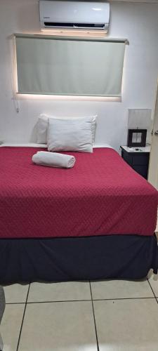 May Apartamento في سان سلفادور: غرفة نوم بها سرير أحمر مع وسادتين