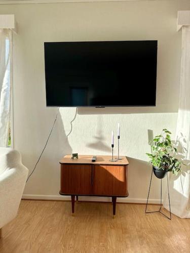 a living room with a flat screen tv on a wall at Romslig kystperle med sjel i Skulsfjord Tromsø in Tromsø
