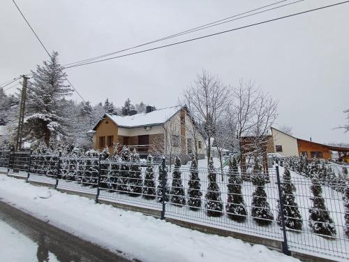 a fence covered in snow in front of a house at Agroturystyka Noclegi Podlesie in Gorlice