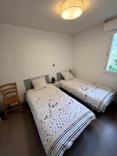 - 2 lits dans une chambre avec une chaise et une fenêtre dans l'établissement Appartement T2 - Cosy 400m des thermes, à Cazaubon