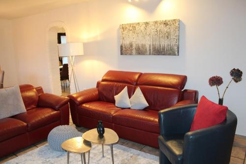 a living room with a brown leather couch and chairs at Ferienhaus MeinWeg in Wassenberg