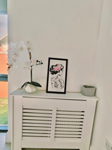 a white table with a vase and flowers on it at Coastal Gem 10 Mins from Dublin Airport in Donabate