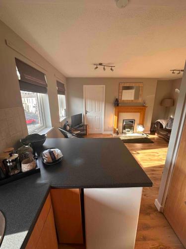 a kitchen with a black counter top and a living room at A Cozy One Bedroom Flat for Two Guests in Carlisle