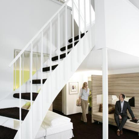 a man and woman standing in a bedroom with a staircase at Gasthaus Rössle in Kirchheim unter Teck