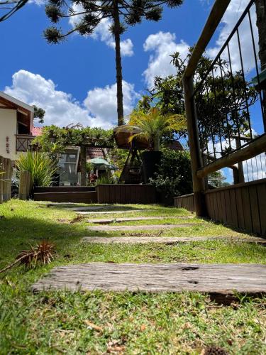 a walkway in a yard with a house in the background at Pousada Cantinho da Serra in Campos do Jordão