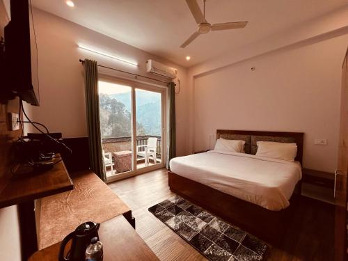 a bedroom with a bed and a large window at Hotel Anantam Residency in Uttarkāshi
