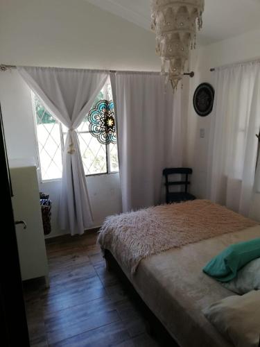 a bedroom with a bed and a window and a chandelier at Casa del Cerro San Javier in Yerba Buena