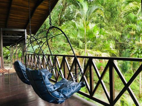 a hammock hanging from a porch with trees at Ávita Lodge in Quesada