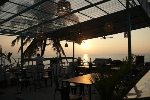 a man sitting at a table at a restaurant overlooking the ocean at Cliff and Coral Varkala, North Cliff in Varkala