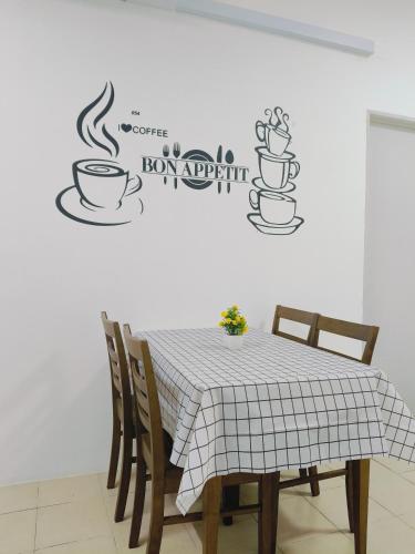a table and chairs with a table and a coffee sign on a wall at Serene Homestay in Tawau