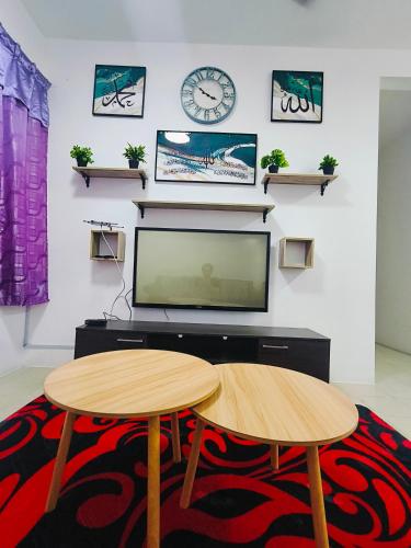a living room with a tv and two tables at Serene Homestay in Tawau