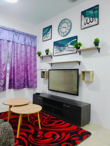 a living room with a flat screen tv and a table and chairs at Serene Homestay in Tawau