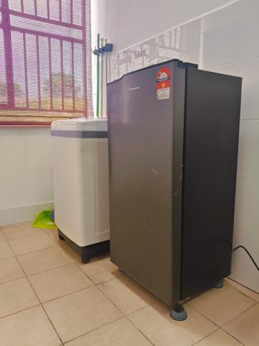 a black refrigerator next to a trash can at Serene Homestay in Tawau