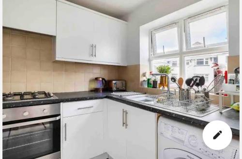 a kitchen with white cabinets and a stove top oven at Town centre White House in Bournemouth